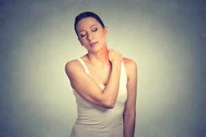 pain. Woman with painful neck shoulder colored in red isolated on gray wall background