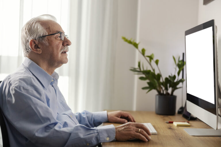 Side view of a senior man using computer at home office