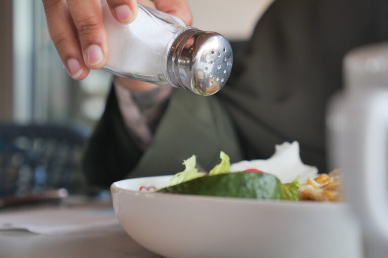 Adding salt to a fresh salad at a dining table