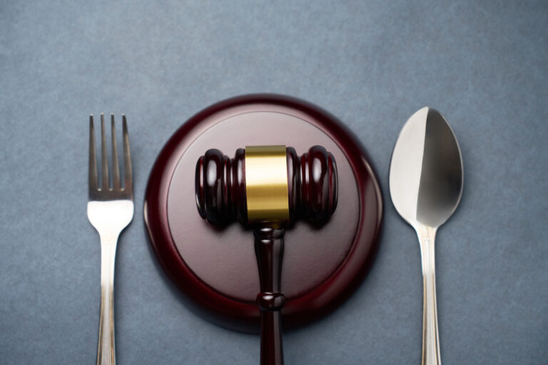 Judges gavel with fork and spoon on a dark background with copy space, close-up