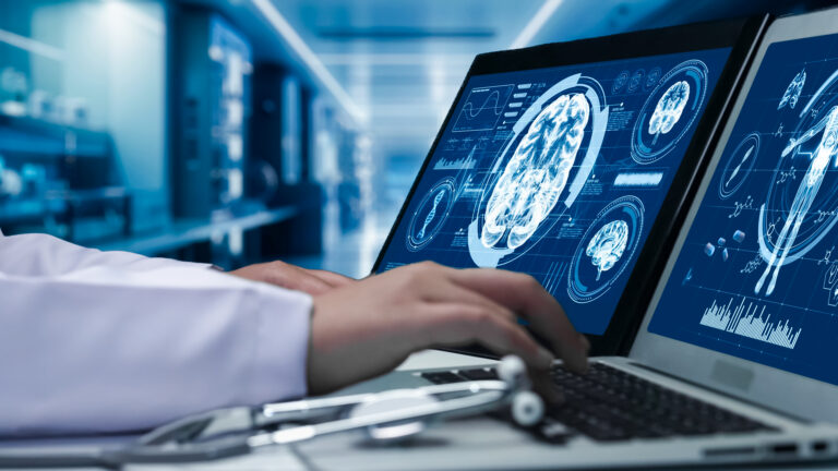 Close up of doctor working on tablet and laptop with brain anatomy. Remedial
