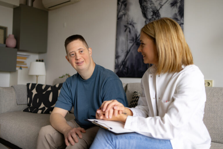 Happy man with Down syndrome and his doctor at home