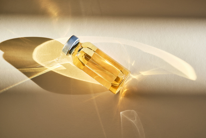 Injection vial with medicinal product in sunlight on beige background